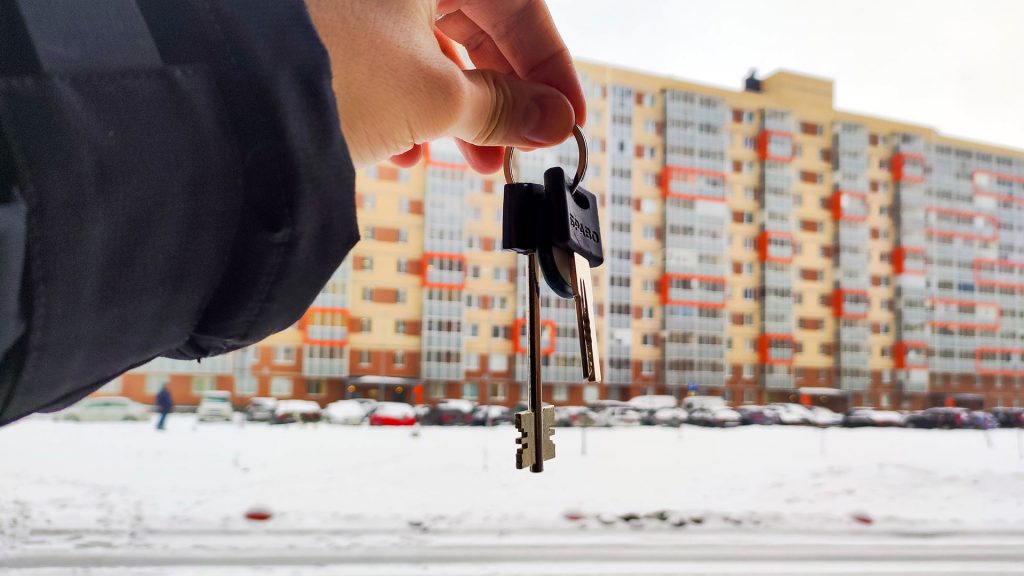 Ключи от квартиры на фоне новостройки зимой