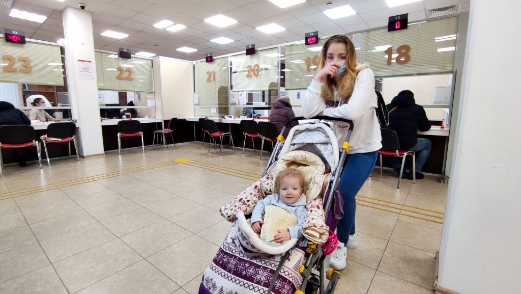 Мать с ребёнком в коляске в МФЦ — оформление документов после регистрации