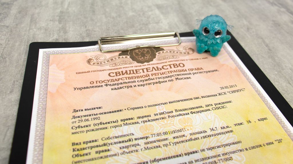 Свидетельство о праве собственности на квартиру и детская игрушка на столе